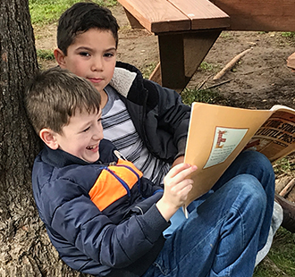 Two students reading together outside